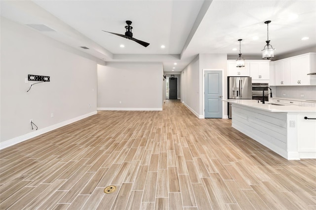 unfurnished living room featuring ceiling fan, light wood-type flooring, and sink