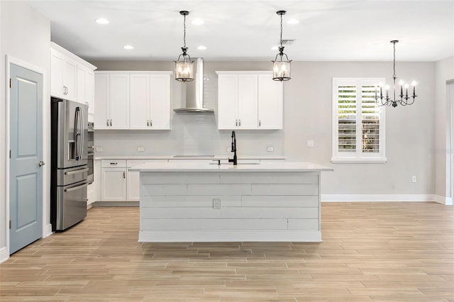 kitchen with sink, wall chimney range hood, stainless steel refrigerator with ice dispenser, pendant lighting, and white cabinets