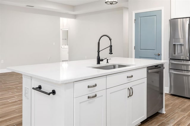 kitchen with a center island with sink, sink, white cabinets, and stainless steel appliances