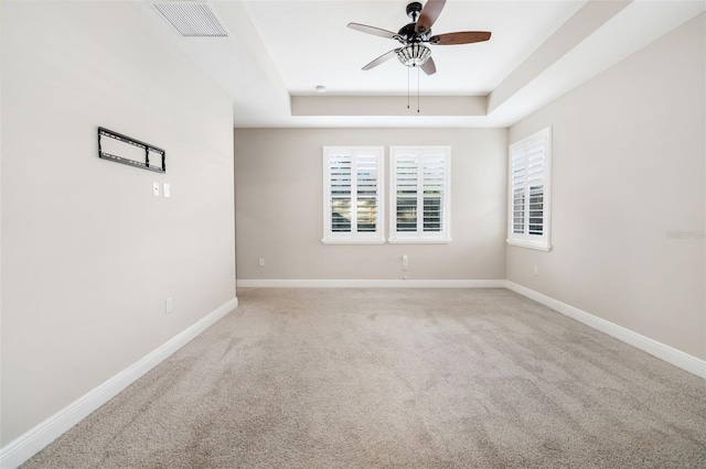 spare room with carpet flooring, ceiling fan, and a raised ceiling