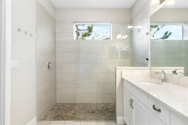 bathroom featuring vanity, a healthy amount of sunlight, and a tile shower