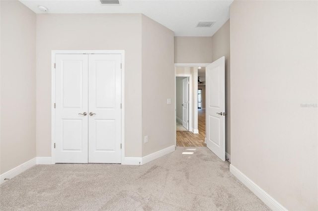 unfurnished bedroom featuring light carpet and a closet