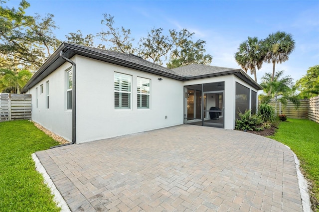 rear view of property featuring a sunroom, a patio area, and a yard