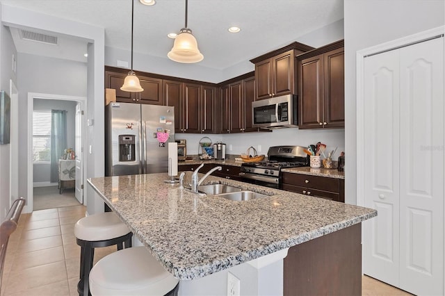 kitchen featuring pendant lighting, sink, an island with sink, and stainless steel appliances