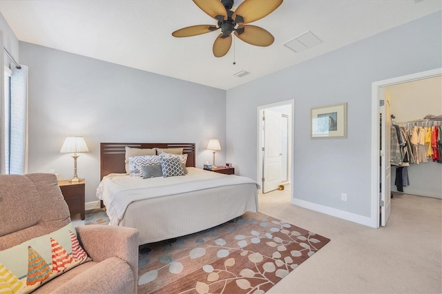 carpeted bedroom with a walk in closet, ceiling fan, and a closet