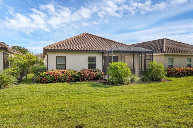 rear view of property with a yard and glass enclosure