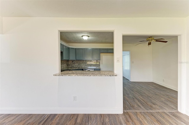 kitchen with dark hardwood / wood-style floors, light stone counters, tasteful backsplash, and ceiling fan