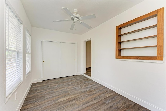 unfurnished bedroom featuring multiple windows, dark wood-type flooring, and ceiling fan