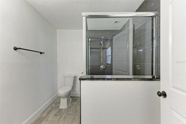 bathroom featuring hardwood / wood-style flooring, toilet, and a shower with door