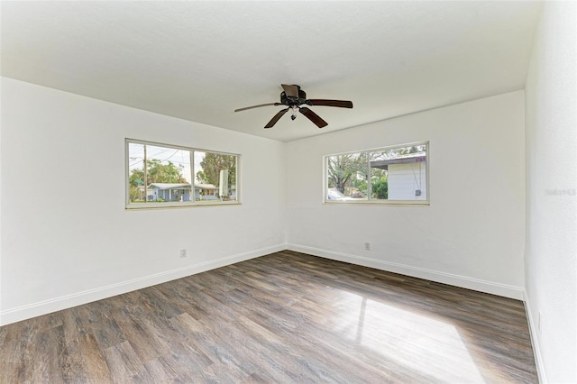 empty room with dark hardwood / wood-style floors, ceiling fan, and a wealth of natural light