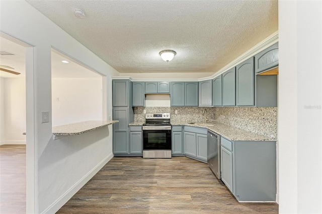 kitchen featuring sink, stainless steel appliances, tasteful backsplash, hardwood / wood-style floors, and a textured ceiling