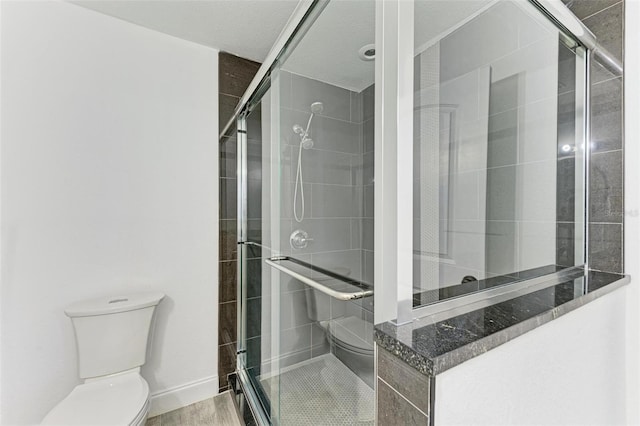 bathroom featuring wood-type flooring, toilet, and a shower with shower door