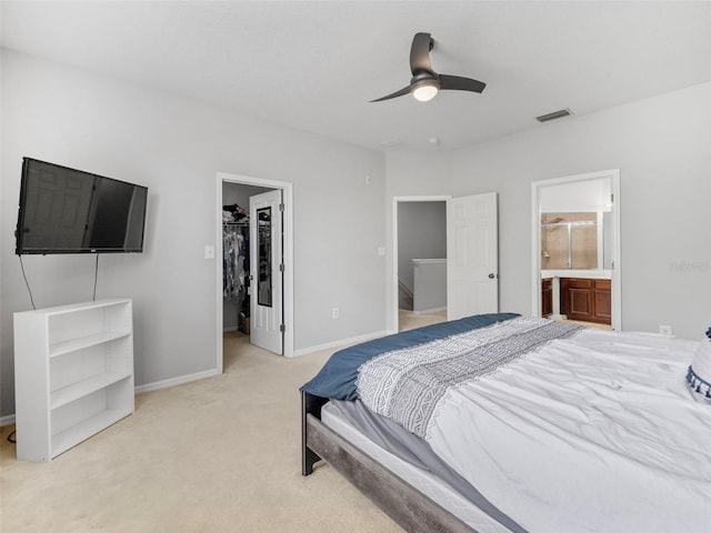 bedroom featuring a spacious closet, light carpet, ensuite bathroom, ceiling fan, and a closet