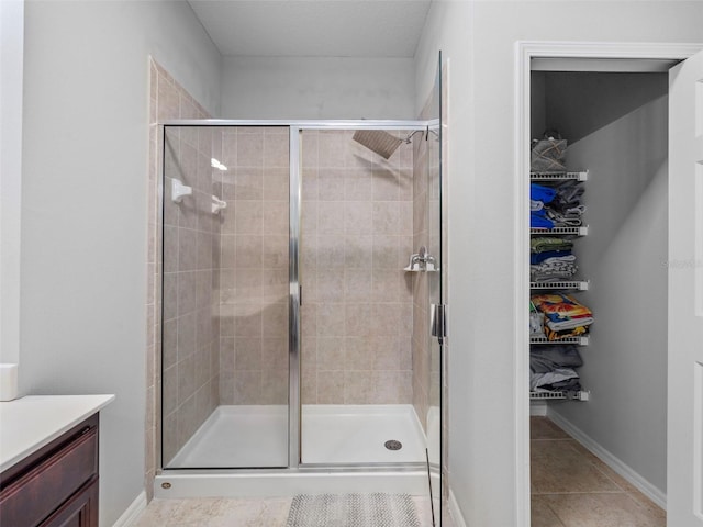 bathroom featuring a shower with shower door, vanity, and tile patterned flooring