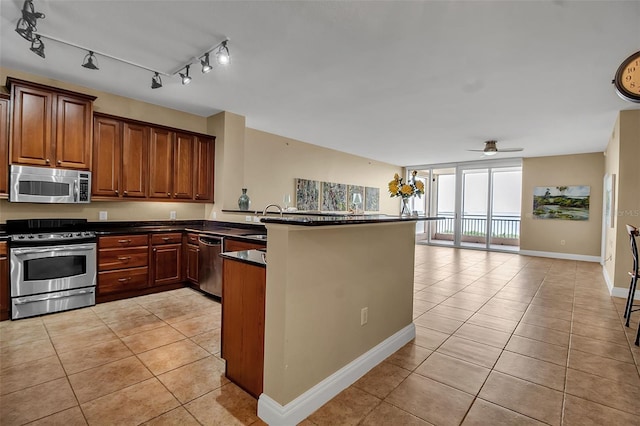 kitchen featuring kitchen peninsula, stainless steel appliances, ceiling fan, sink, and light tile patterned floors