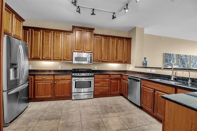 kitchen featuring light tile patterned floors, stainless steel appliances, dark stone counters, and sink