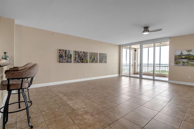 empty room featuring light tile patterned floors, floor to ceiling windows, and ceiling fan