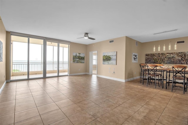 empty room featuring ceiling fan, light tile patterned floors, and a wall of windows