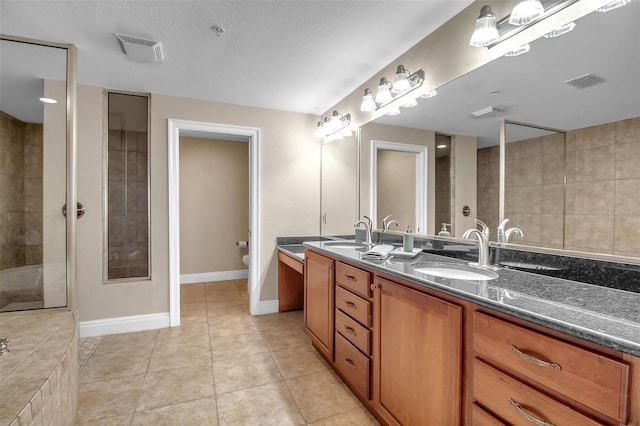 bathroom with tile patterned floors, vanity, tiled shower, and toilet