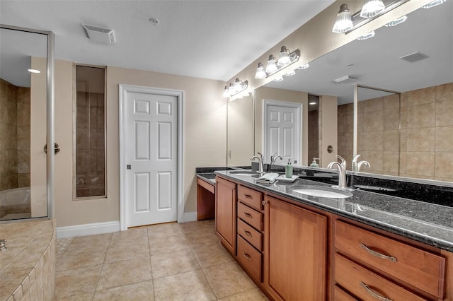 bathroom with a tile shower, tile patterned flooring, and vanity