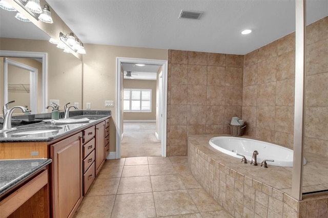 bathroom with tile patterned floors, tiled tub, ceiling fan, and vanity