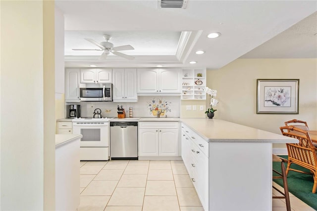 kitchen featuring a peninsula, visible vents, a kitchen breakfast bar, appliances with stainless steel finishes, and a raised ceiling