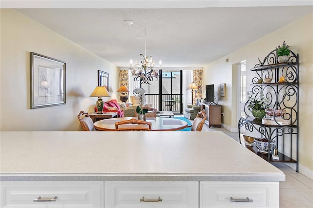 kitchen featuring a notable chandelier, light countertops, expansive windows, open floor plan, and white cabinets