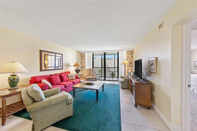 living area with light tile patterned floors, a textured ceiling, visible vents, baseboards, and a wall of windows