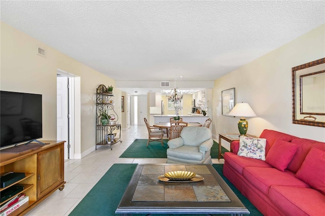 living room featuring light tile patterned floors, a textured ceiling, a chandelier, and visible vents