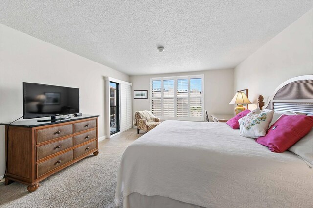 bedroom featuring light carpet, access to outside, and a textured ceiling