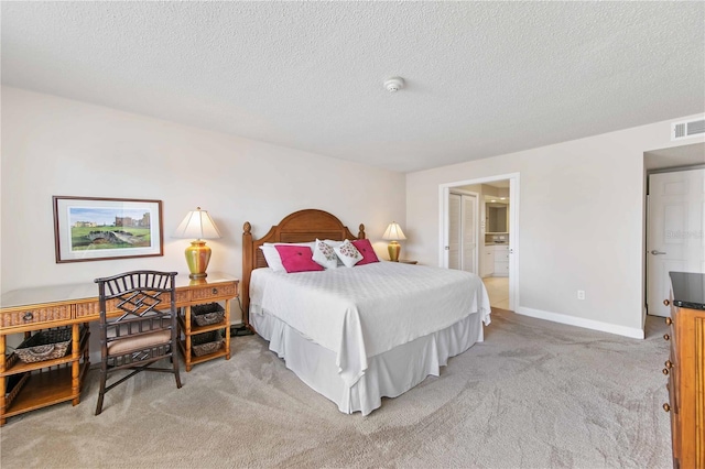 bedroom with baseboards, visible vents, connected bathroom, light colored carpet, and a textured ceiling