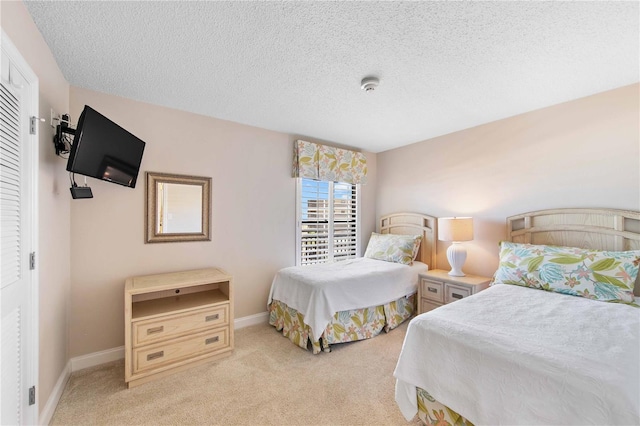 bedroom with light carpet, baseboards, and a textured ceiling