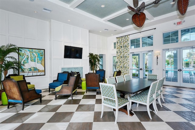 dining space with coffered ceiling, ceiling fan, a high ceiling, french doors, and beamed ceiling