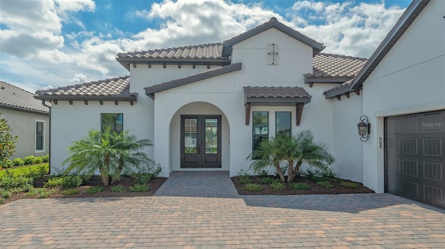 view of exterior entry with french doors, a tiled roof, and stucco siding