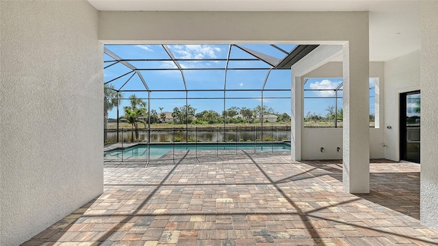 view of swimming pool with a patio area, glass enclosure, and a water view