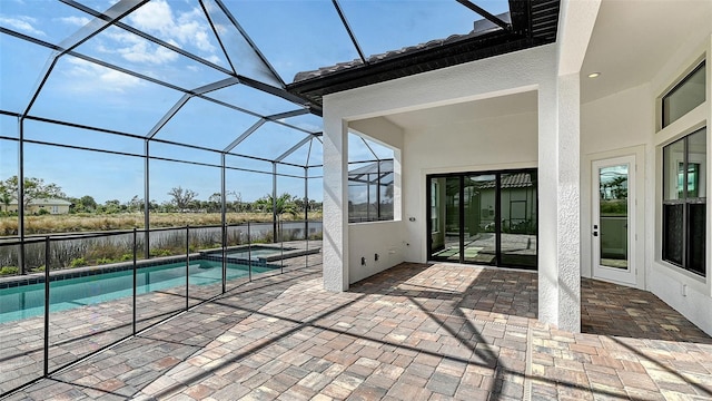 view of swimming pool with glass enclosure, a patio area, and a water view