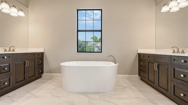 bathroom with marble finish floor, two vanities, a sink, and a soaking tub