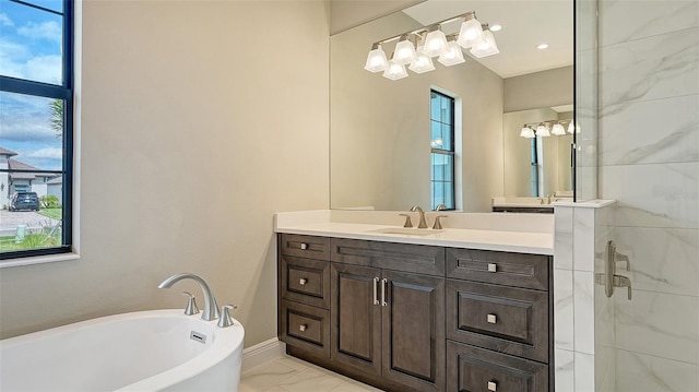 full bath featuring a healthy amount of sunlight, marble finish floor, a freestanding tub, and vanity