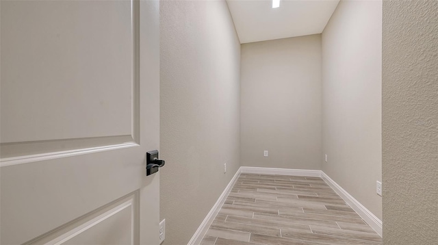 interior space with wood tiled floor, baseboards, and a textured wall