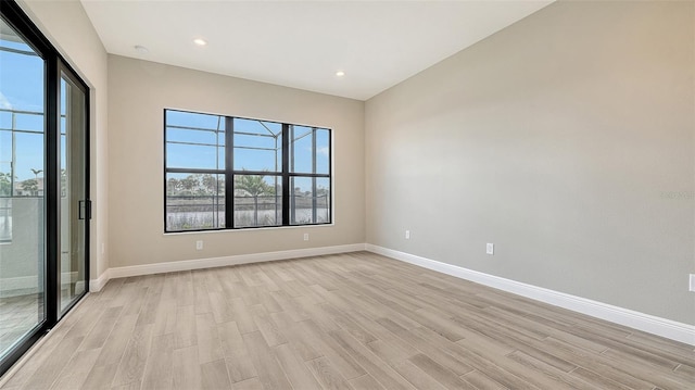 spare room featuring light wood-type flooring, baseboards, and recessed lighting