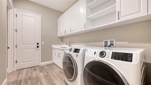 washroom featuring a sink, baseboards, independent washer and dryer, cabinet space, and wood tiled floor