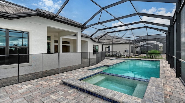 view of swimming pool with glass enclosure, a patio area, and a pool with connected hot tub