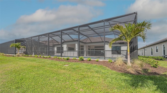 back of house with glass enclosure, an outdoor pool, and a yard