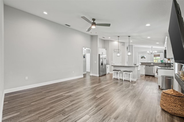 living room with sink, ceiling fan with notable chandelier, and hardwood / wood-style flooring