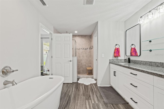 bathroom featuring independent shower and bath, vanity, a textured ceiling, and hardwood / wood-style floors