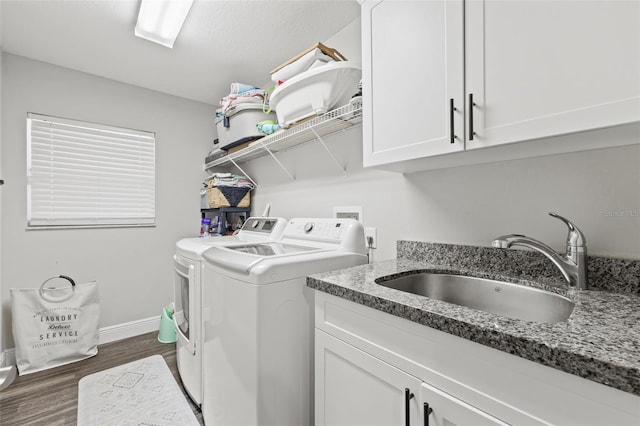 clothes washing area featuring sink, cabinets, washer and clothes dryer, and dark hardwood / wood-style floors