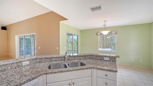 kitchen with sink, white cabinetry, light tile patterned floors, pendant lighting, and light stone countertops