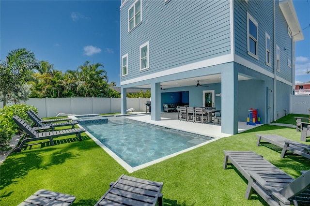 back of house with a fenced in pool, ceiling fan, a lawn, and a patio