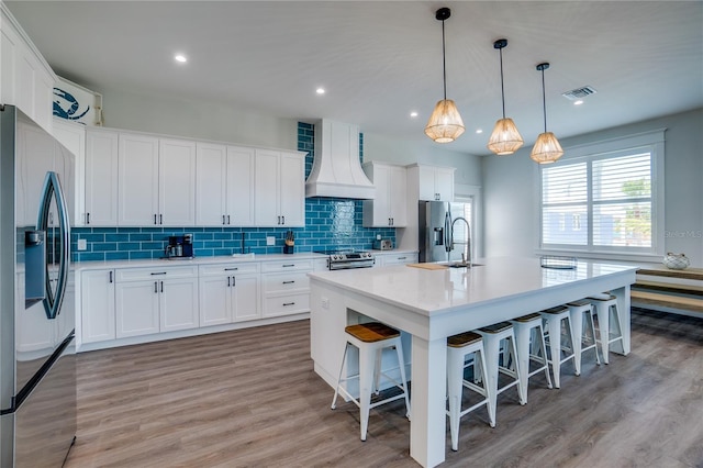 kitchen with white cabinets, custom exhaust hood, and stainless steel appliances