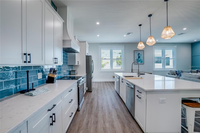 kitchen featuring sink, hanging light fixtures, a center island with sink, white cabinets, and appliances with stainless steel finishes